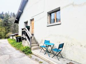 dos sillas y una mesa al lado de un edificio en appart proche de la frontière, en Les Gras