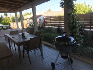 einen Grill auf einer Terrasse mit einem Tisch, einem Tisch und Stühlen in der Unterkunft Villa Artemis Leto in Artemida