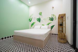a bedroom with a large bed with green plants on the wall at Vy Apartment- New Life Ha Long in Ha Long