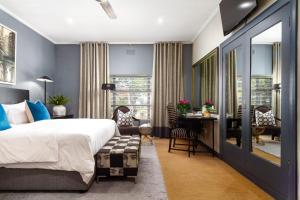 een slaapkamer met een bed, een bureau en een tafel bij Life & Leisure Boutique Guesthouse in Stellenbosch