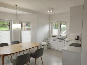 佐伯的住宿－Domek Pod Tatrami，白色的厨房配有木桌和椅子