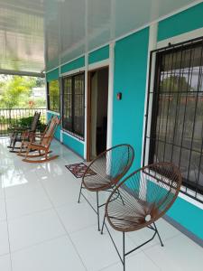 un porche con 2 sillas y un edificio azul en Casa Vista Arenal, en Fortuna