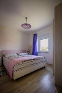 斯盧尼的住宿－Apartman Milka，一间卧室配有一张床和一个带紫色窗帘的窗户