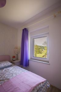 斯盧尼的住宿－Apartman Milka，一间卧室配有一张床和一个带紫色窗帘的窗户