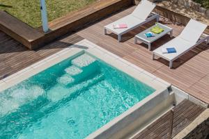 einen Pool mit 2 Stühlen und einem Tisch in der Unterkunft Villa SEA SOUL - Luxury style with direct access to sea in Porto Taverna