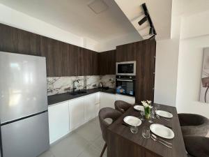 Una cocina con una mesa con sillas y un refrigerador. en East Gate Luxury Apartment, en Skopje