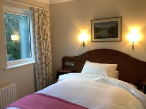 a bedroom with a bed with two lamps and a window at Gleann Fia Country House in Killarney