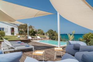 eine Terrasse mit Stühlen und einen Pool mit Sonnenschirm in der Unterkunft Villa SEA SOUL - Luxury style with direct access to sea in Porto Taverna