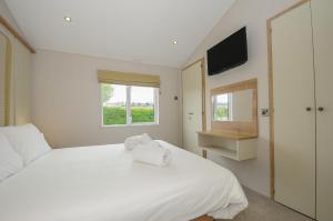 a white bedroom with a white bed and a window at Lodge 74 at Riviera Bay Coastal Retreat in Brixham +33 photos
