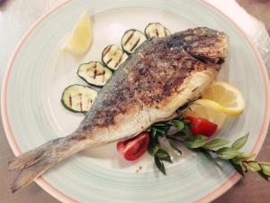 a fish on a plate with cucumbers and vegetables at b&b il Portico Orgosolo in Orgosolo