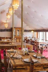 une salle à manger avec des tables et des chaises en bois dans l'établissement Caravanserai Luxury Desert Camp, à Merzouga