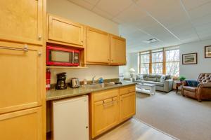 a kitchen with wooden cabinets and a living room at New Kensington Vacation Rental with Shared Patio! in New Kensington