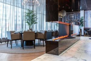 فندق راديسون بلو سكاي في تالين: غرفة طعام بها موقد وطاولات وكراسي