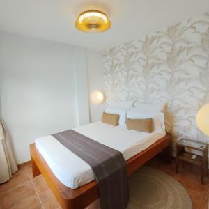 um quarto com uma cama com lençóis brancos e uma parede em Facing the ocean em Santa Maria de Guia de Gran Canaria