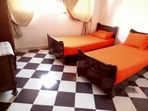 two beds in a room with a checkered floor at Hamed Guest House in Aswan