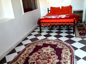 a bedroom with a red bed and a checkered floor at Hamed Guest House in Aswan