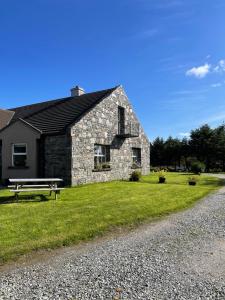a stone house with a bench next to a gravel road at Shanakeever Farm - 2 Bedroom Apartment in Clifden