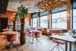 een restaurant met tafels en stoelen en een grote kroonluchter bij Hotel Les Eleveurs in Halle