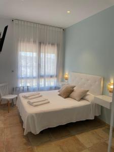 1 dormitorio con 1 cama blanca grande y toallas. en El Escondido de Zahara, en Zahara de los Atunes