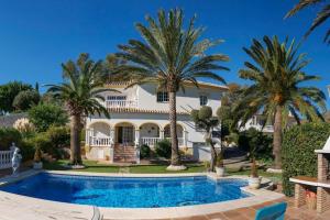 une grande maison avec des palmiers et une piscine dans l'établissement Villa Puerto de la Luz, à Mijas