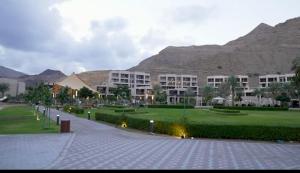 een groot appartementencomplex met bergen op de achtergrond bij خليج مسقط in Qantab