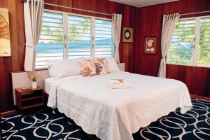 a bedroom with a white bed and a window at Casa Al Mar, St. George's Caye - Belize in Belize City