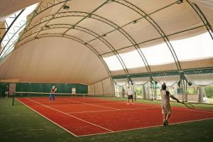 eine Gruppe von Menschen, die auf einem Tennisplatz Tennis spielen in der Unterkunft Jabłoń Lake Resort in Pisz