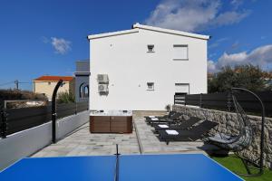a ping pong table on a patio with a white building at Simaruna in Maslenica