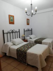 Una habitación con tres camas y una lámpara de araña. en Apartmentos Corona, en Cazorla