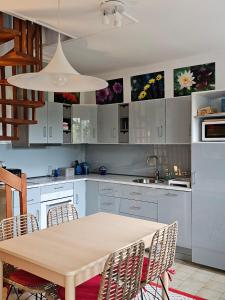 a kitchen with white cabinets and a wooden table at Clair logis in Giverny