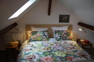 a bedroom with a bed with floral sheets and pillows at Clair logis in Giverny