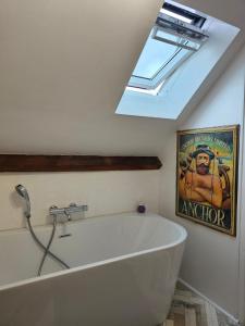 een badkamer met een wit bad en een dakraam bij Clair logis in Giverny