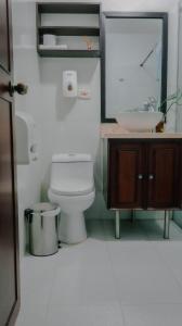 ein Badezimmer mit einem WC, einem Waschbecken und einem Spiegel in der Unterkunft Boutique Portón De Granada in Cali