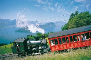 a steam engine train on the tracks with a group of people at Cozy House above Lake Lucerne in car-free Vitznau Mittlerschwanden at Mount Rigi railway in Vitznau