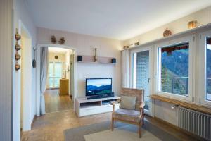 ein Wohnzimmer mit einem TV und einem Stuhl in der Unterkunft Cozy House above Lake Lucerne in car-free Vitznau Mittlerschwanden at Mount Rigi railway in Vitznau