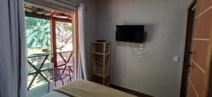 a room with a bed and a tv and a window at Pepalantus Flats in Santana do Riacho