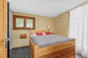 sypialnia z drewnianym łóżkiem z czerwonymi poduszkami w obiekcie Grand Chalet Standing Avec Jacuzzi à Chamrousse ski 1750 w mieście Chamrousse