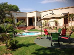 a patio with a table and chairs and an umbrella at Amigos Bed & Breakfast - No loadshedding in Nelspruit