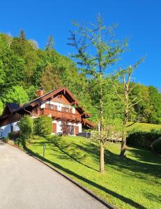 a house with a tree in front of a driveway at Alpenparadies nahe Salzburg Sauna & Whirlpool in Adnet