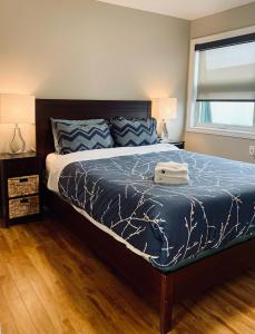 a bedroom with a bed with a blue comforter and a window at Comfy 2-BDRM, Historic North End in Halifax