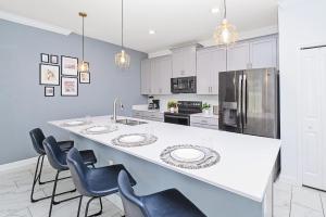 a kitchen with a large white counter and chairs at Upstay - ChampionsGate Home w Private Pool & BBQ in Kissimmee