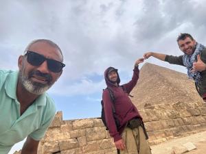 Tres hombres parados en la cima de una pirámide. en Pyramids Temple Guest House en El Cairo