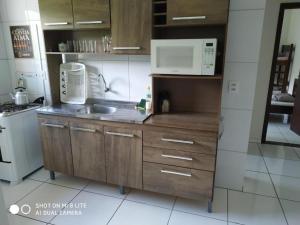 a kitchen with a sink and a microwave at Pousada Agradável Pomerode in Pomerode