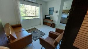 a living room with two chairs and a television at Pousada Agradável Pomerode in Pomerode