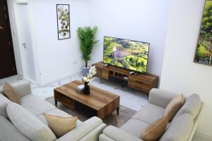 a living room with two couches and a flat screen tv at MasdarCity Bliss 2BR apartment in Abu Dhabi