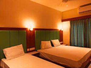 a hotel room with two beds and a window at Hotel Harshanaa Elite in Kanyakumari