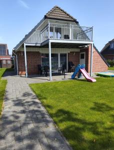 a house with a playground with a slide in the yard at Ferienhaus Krabbe in Friedrichskoog-Spitze/ Nordsee in Friedrichskoog