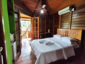 a bedroom with a bed with white sheets and a window at Hotel Fazenda Igarapés in Igarapé