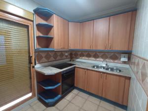 Una pequeña cocina con gabinetes de madera y un fregadero. en Apartmentos Corona, en Cazorla