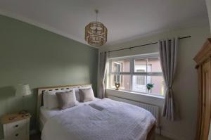 1 dormitorio con cama blanca y ventana en Shanakeever Farm - 2 Bedroom Apartment en Clifden